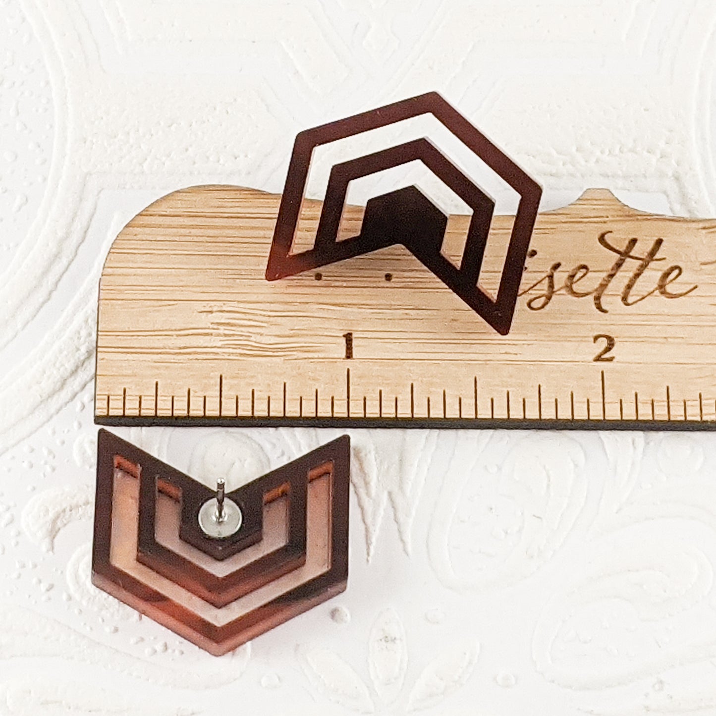 Warm translucent brown and gold tortoiseshell acrylic cut into Irregular Radiating Hexagon Earrings by a ruler, showing the max height is 1 inch. By Isette