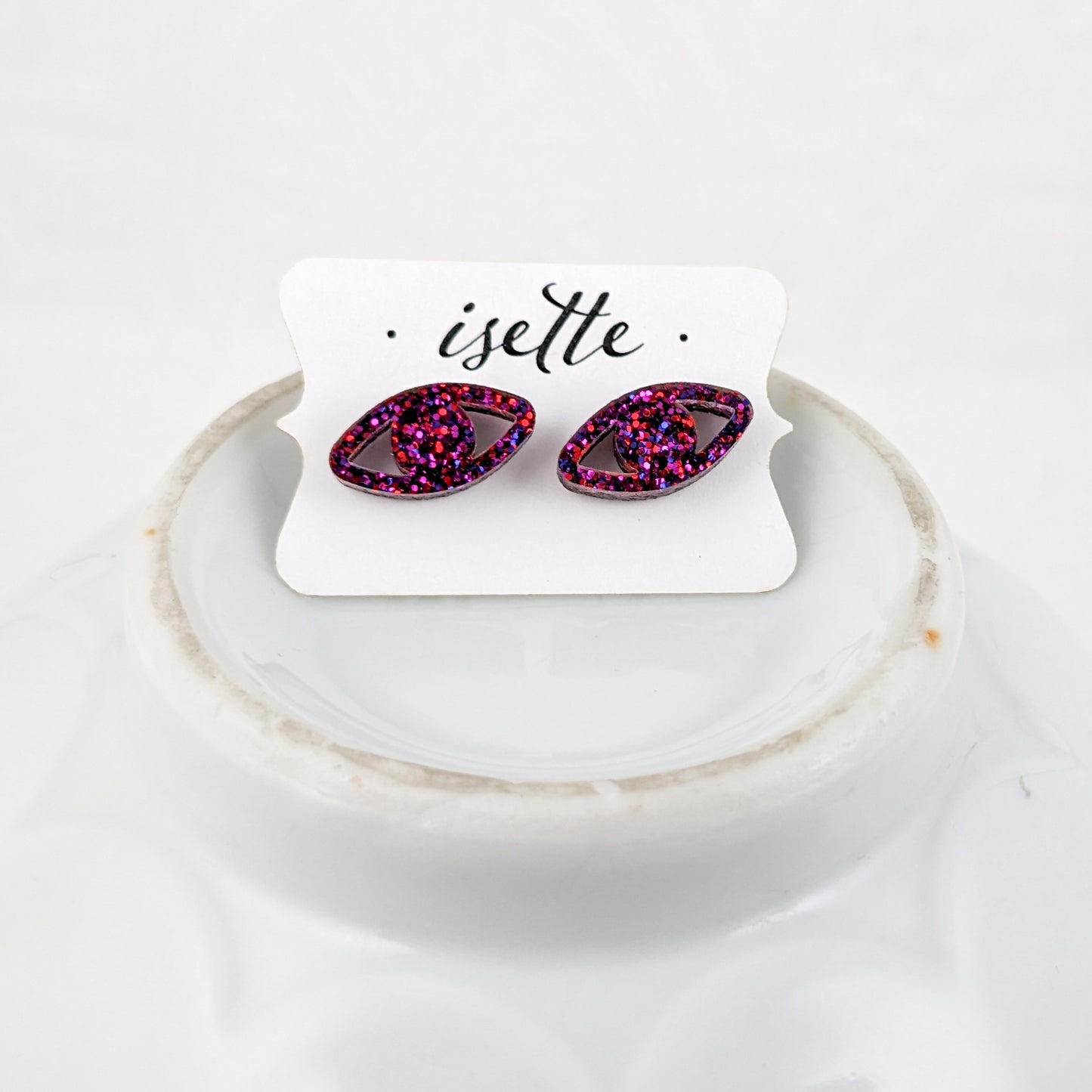 Eye shaped stud earrings made with ruby sparkle acrylic and stainless steel posts on Isette card